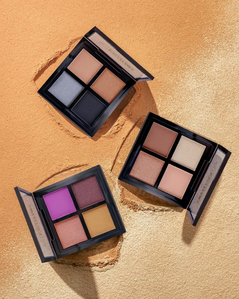 Colorful eyeshadow palettes on a sand-textured backdrop, perfect for beauty and makeup themes.